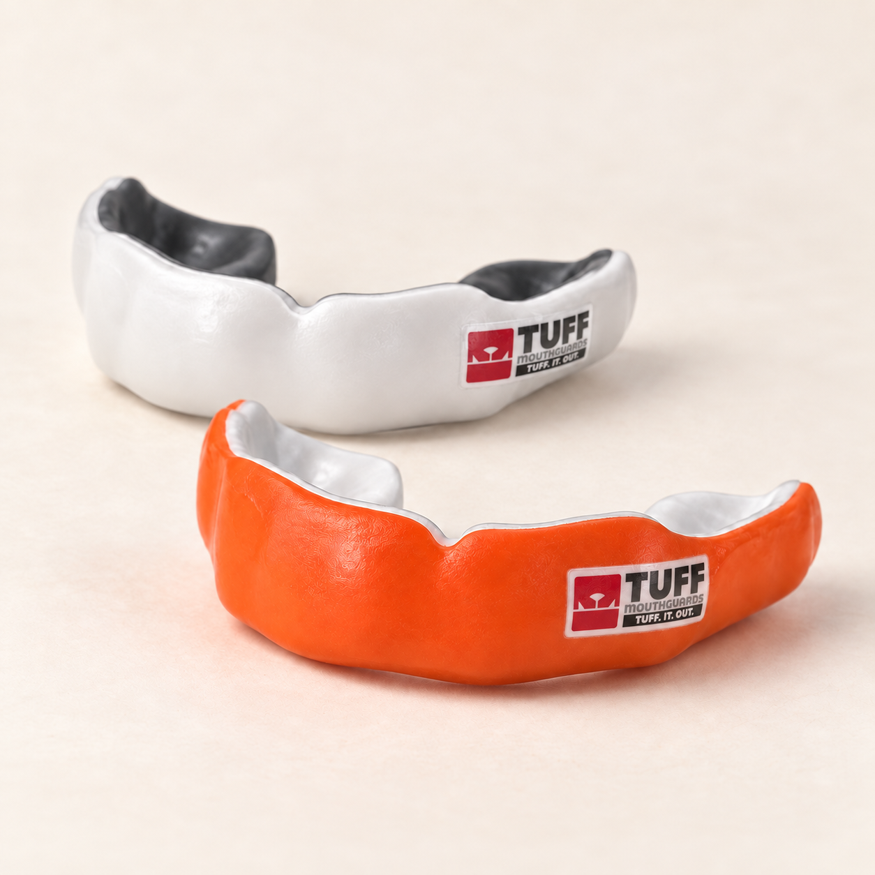 Orange and white custom sports mouthguards with TUFF logos on the outer sides